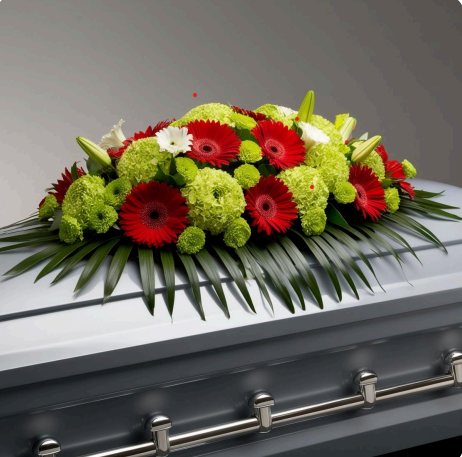 Red and green casket spray with gerbera daisies, hydrangeas, lilies, and tropical greens - funeral floral arrangement by LUXE Macon