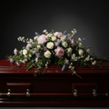 Floral arrangement on a dark wooden casket against a black background
